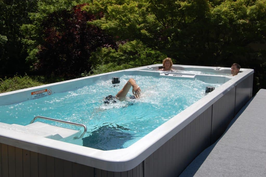 a couple swimming in a swim spa in their Texas backyard. A perfect swim solution for them.