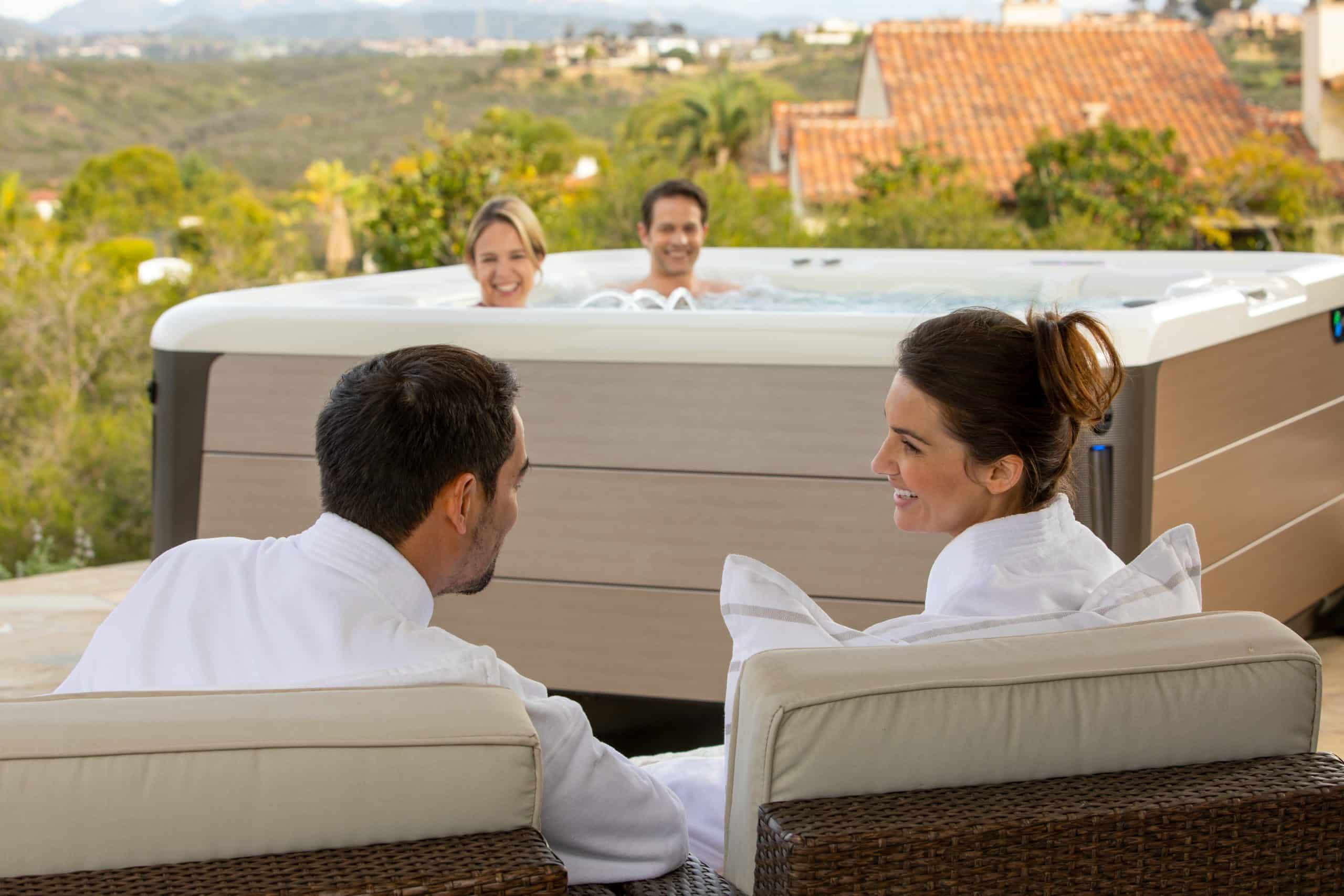 Couple enjoys hot tub while friends look on in fluffy robes